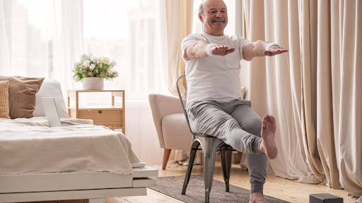 An senior adult man with mobility issues doing a chair-based excercise.